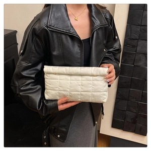 Detailopname van witte gewatteerde clutch met ruitjespatroon en gouden knoopdetails op de tas