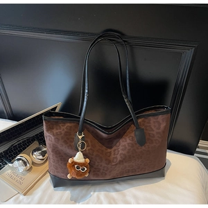 Close-up of leopard print tote bag with black leather trim and cute bear charm detail