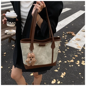 Detail view of canvas tote bag with brown PU leather trim and fuzzy bear pendant charm