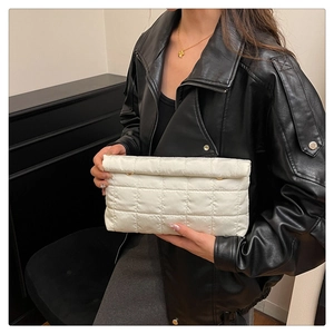 Detail van een witte gewatteerde clutch met ruitjespatroon vastgehouden door model