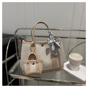 Detail of canvas tote bag with brown faux leather trim, mini pouch, and floral scarf accent