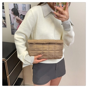 Detail van de kaki gewatteerde cloud clutch met geborduurd ruitpatroon vastgehouden