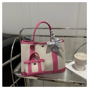 Detail of canvas tote bag with rose pink leather trim, silk scarf, and mini pouch