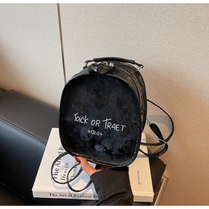 Detail of black suede backpack with Trick or Treat lettering on leather surface