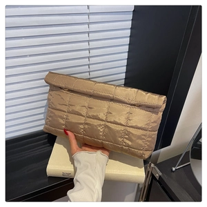 Detailoverzicht van de beige gewatteerde clutch met zachte textuur en metalen ringen