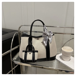 Detail view of canvas tote bag with black leather trim and decorative silk scarf accessory