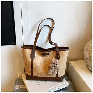 Dettaglio della borsa tote grande con trama vintage, bordi in pelle e ciondolo a cucciolo