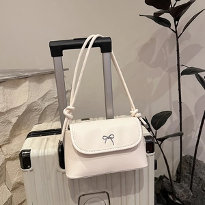 Elegant cream small crossbody bag with silver bow accent on a suitcase handle