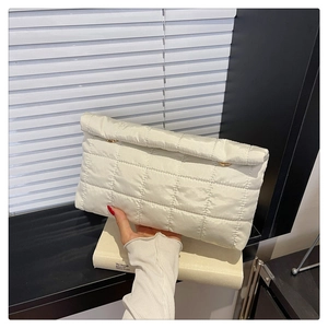 Gedetailleerde weergave van de crème gewatteerde nylon clutch met gouden ringen