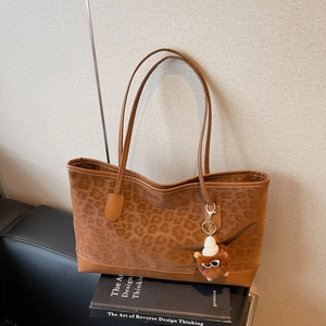 Retro leopard print large capacity tote bag with plush lion charm on a leather sofa