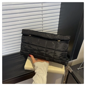 Detail van de zwarte gewatteerde clutch met ruitstiksel en gouden metalen sluiting
