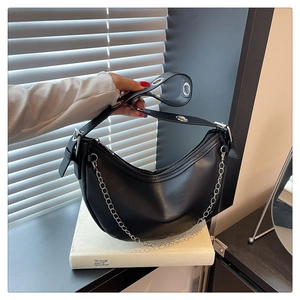 Detail of black crescent hobo bag featuring silver chain and metal eyelet shoulder strap
