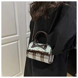 Detail of sweet vintage plaid handbag with bow and heart pendant worn by a model