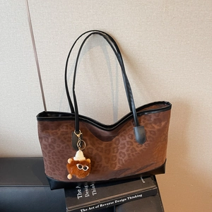 Large leopard print tote bag with black leather straps and a cute plush bear pendant