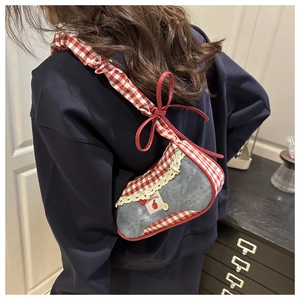Close-up of a blue denim crossbody bag with red gingham trim and cherry appliqué detail