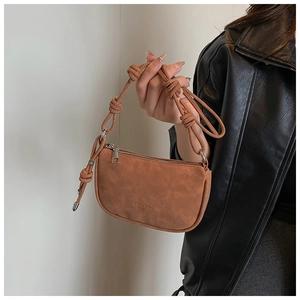 Détail du sac en cuir marron texturé avec bandoulière ornée de nœuds décoratifs élégants