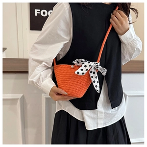 Détail du sac seau tissé orange avec nœud à pois et fermoir en perle élégant