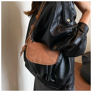 Détail d'un petit sac carré marron avec bandoulière nouée et boucle métallique