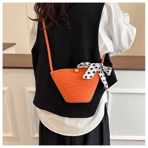 Détail du sac seau tissé orange avec fermoir perle et nœud en soie à pois élégant