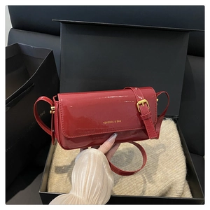 Close-up of red patent leather crossbody bag with gold lettering in a black gift box