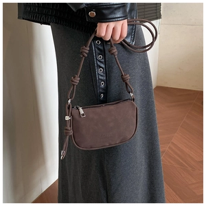 Détail du sac hobo mat marron foncé avec des nœuds décoratifs sur la bandoulière