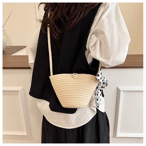 Détail du sac seau en paille avec fermoir perle et foulard à pois noir et blanc