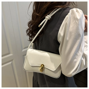 Detail der weißen Leder-Achseltasche mit goldenem Drehverschluss und Knotendetail am Gurt