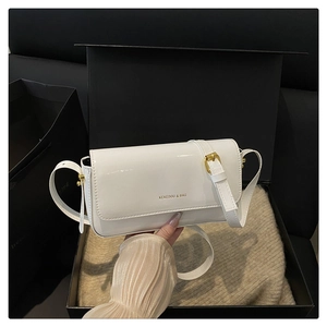Detail of glossy white flap shoulder bag with gold hardware on a gift box background
