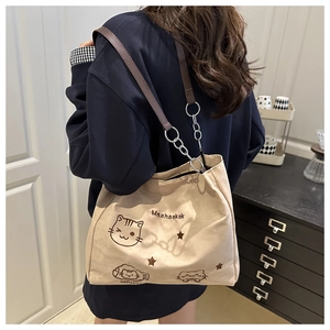 Detail of beige nylon tote bag with cat illustration and brown leather shoulder strap