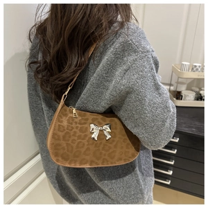 Détail du sac sous l'aisselle à imprimé léopard avec boucle papillon argentée porté