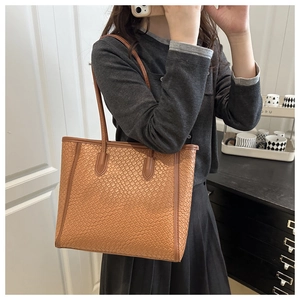 Detailed close-up of brown woven texture and slim double straps on a large tote bag