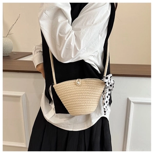 Détail du sac seau tissé beige avec boucle perle et accessoire foulard à pois