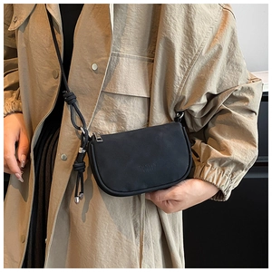 Sac bandoulière demi-lune noir mat minimaliste avec détail logo porté par mannequin