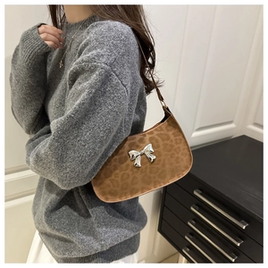 Détail du sac léopard avec charm papillon argenté porté par un mannequin femme