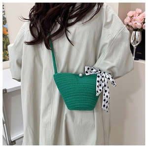 Détail du sac seau tissé avec bouton perle blanche et ruban décoratif à pois noirs