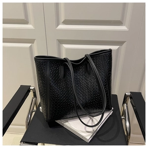 Detailed close-up of premium black woven leather tote bag texture on a designer chair