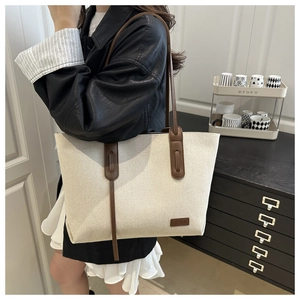 Vista dettagliata della borsa tote in tela bianco avorio con manici lunghi in pelle marrone
