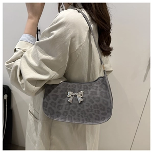 Détail du sac sous l'aisselle à motif léopard gris avec nœud argenté porté sur un manteau