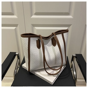 Close-up of woven texture white tote bag with brown straps on minimalist furniture