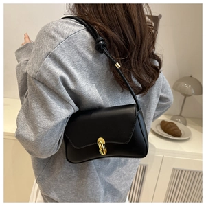 Détail d'un sac à bandoulière en cuir mat noir avec fermoir doré et sangle à nœuds