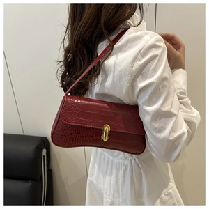 Close-up of deep red crocodile texture leather underarm bag with gold metal buckle