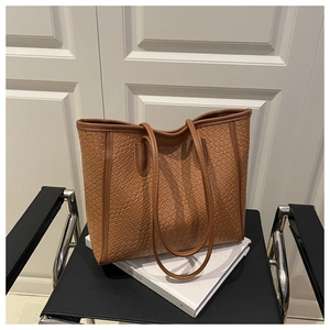 Detail of a brown woven texture tote bag made of premium PU leather on a chair