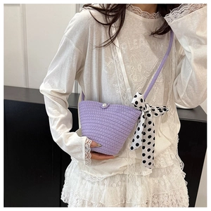 Détail du sac seau tissé violet clair avec bouton perle et foulard à pois élégant
