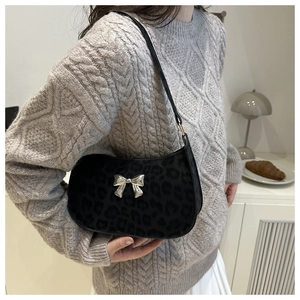 Détail du sac baguette noir à imprimé léopard avec nœud papillon en métal argenté brillant