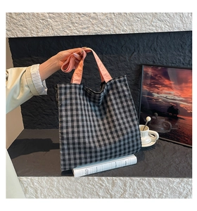 Gros plan d'un sac cabas à carreaux noir et blanc avec des anses roses contrastées