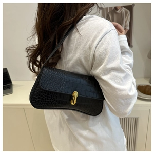 Detail of black crocodile texture baguette bag with golden oval twist lock clasp