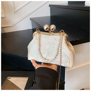 Detail of satin clutch with bamboo print, large pearl clasp, and gold metal frame