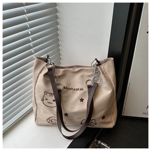 Detail of beige canvas tote bag with star embroidery and brown leather chain strap