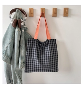 Détail du sac cabas en toile à damier avec large bandoulière orange vif en ambiance lifestyle