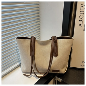 Dettaglio macro della borsa tote in tela beige con etichetta in pelle marrone scuro